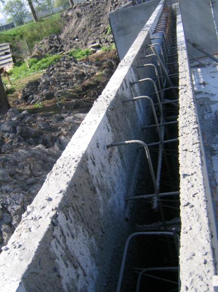 woodenhouse-026.jpg - Hier een duidelijk beeld van de .binnenzijde van de betonnen holle wand. Duidelijk zijn de hoogte verschillen te zien van de binnen en buitenwand. De hoge betonijzers die in een knik naar beneden lopen maken de verbinding met de vloerdelen van de begane grond (de systeem vloer). Ook zien we dieper in de wand de beton ijzers die de twee delen aan elkaar vast houden.