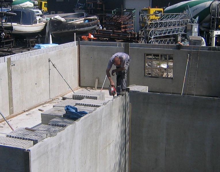 woodenhouse-029.jpg - Om luchtinsluiting in het beton te vermijden wordt met een trilnaald al het lucht weggetrild om een zon hecht mogelijk beton te verkrijgen