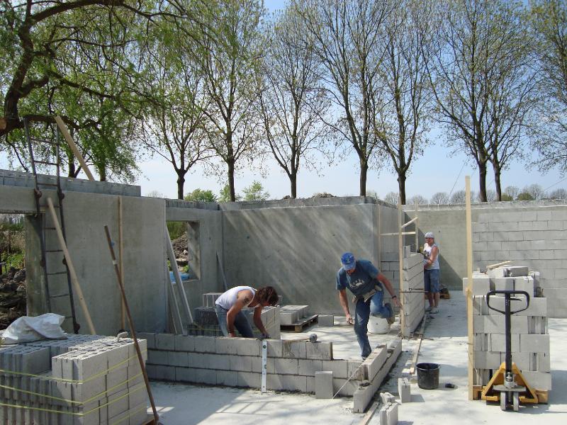 woodenhouse-031.jpg - De draagmuren en natuurlijk ook de scheidingwanden worden gemetseld. De pallets met stenen zijn dicht bij het werk gezet om onnodig  sleepwerk te voorkomen.