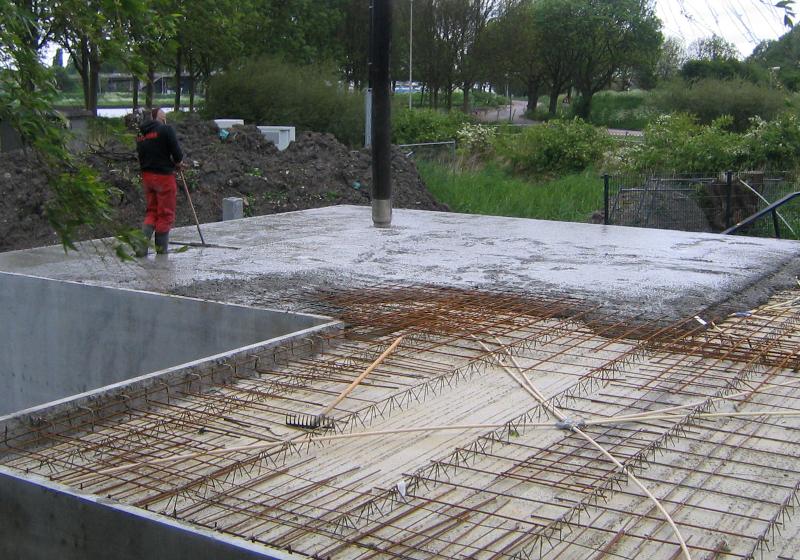 woodenhouse-039.jpg - Het beton wordt gestort en uitgeracheld met een brede platte hark en weer getrild om luchtinsluiting te voorkomen.