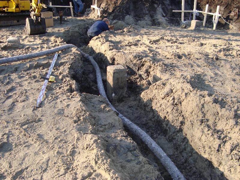 woodenhouse-011.jpg - On met en place des tuyaux perforés pour l'écoulement des eaux souterraines. Ces tuyaux sont installés de façon permanente et rejettent l'eau dans un puits en contrebas, ce qui permet l'évacuation de l'eau en cas de trop plein.