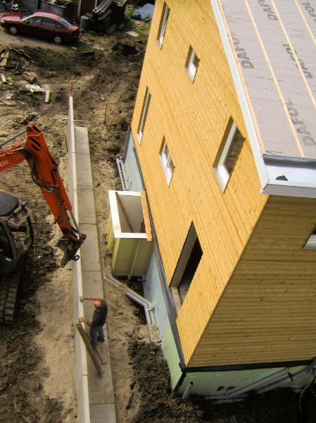 woodenhouse-053.jpg - La maison est presque terminée. Il faut encore s'occuper de l'égalisation des sols. La terre polluée est déversée contre la cave en une première couche. Puis on couvre d'un film protecteur imperméable avant de combler le reste avec de la terre compostée propre.